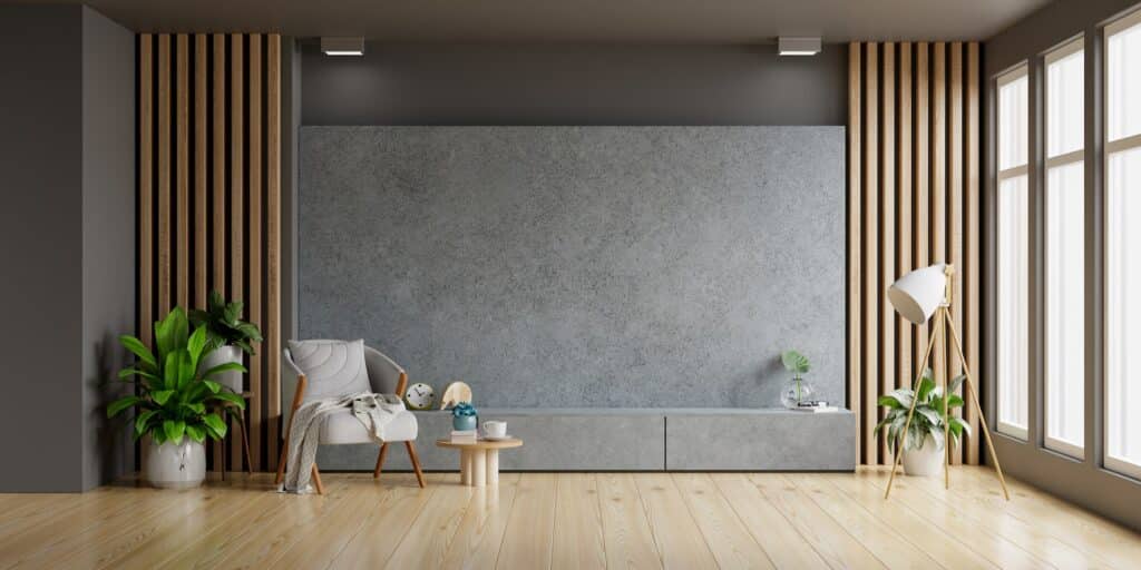 Concrete cabinet TV in modern living room with armchair and plant on concrete wall.